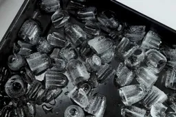 Bullet ice displayed in a black enamel baking tray showing partly melted ice after the machine was left to run for 8 hours.