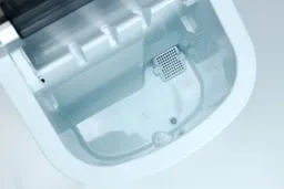 The empty water tank of the Frigidaire EFIC189 countertop portable bullet ice maker with the water guard shown in the right hand upper corner.