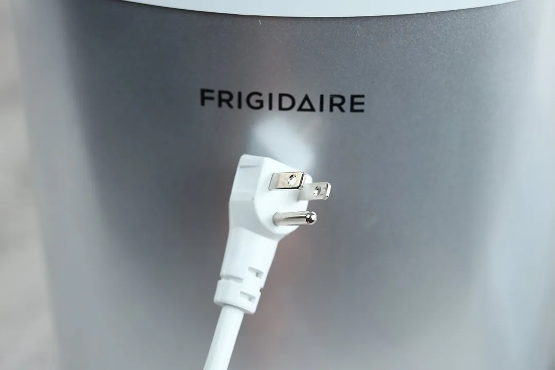 The white electric cord and three prong plug of the Frigidaire EFIC189 countertop portable bullet ice maker picture against the front of the machine.