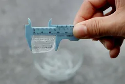 A measuring tong holding a typical ice bullet made in the Frigidaire EFIC189 countertop portable bullet ice maker. The ice bullet measures 1.1 inches in length.