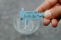 A measuring tong holding a typical ice bullet made in the Frigidaire EFIC189 countertop portable bullet ice maker. The ice bullet shows a thickness of 0.5 inches.