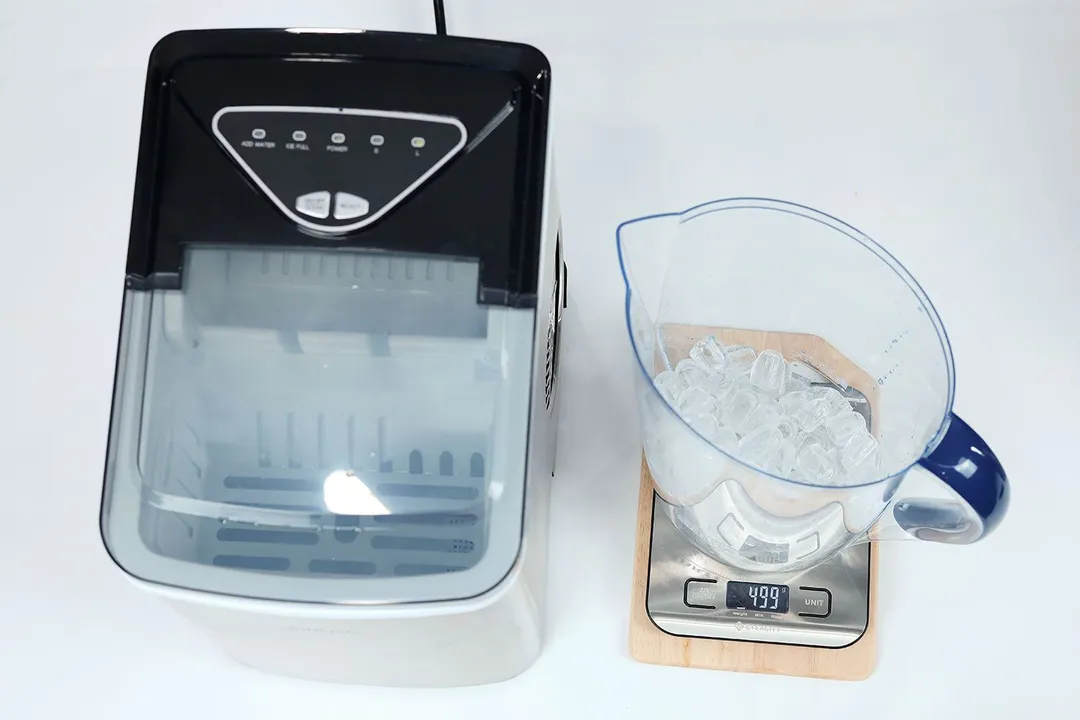 One full basket of ice from a portable ice maker being measured in a jug on a scale recording a total of 499 grams of ice.