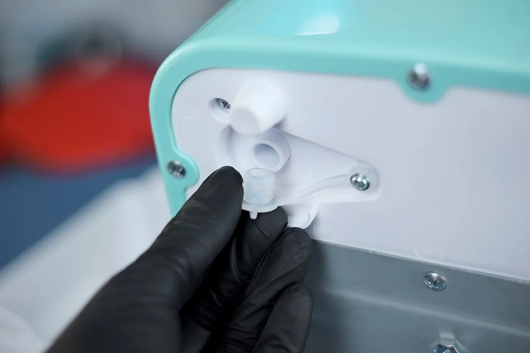 A silicone plug being removed from the bottom of a portable ice maker.