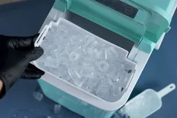 A full basket of ice being removed from a portable countertop ice maker.