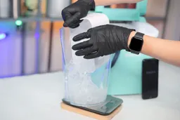A basket of ice from a portable ice maker being emptied into a jug resting on a scale.