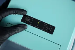 A close up of the control panel on a portable ice maker with two fingers indicating the relative size.