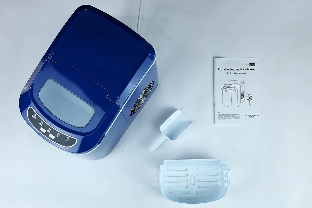 The navy blue Vivo Home countertop ice maker picture from above with the contents of the box displayed to right namely the user manual, a removable ice basket, and an ice scoop.