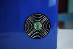 A close up of the body and extractor fan of a navy blue portable ice maker.