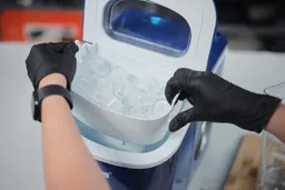 A full basket of ice being removed from a countertop bullet ice maker.