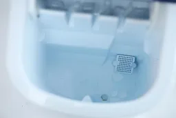 A close up of water inside the reservoir of a portable countertop ice machine.
