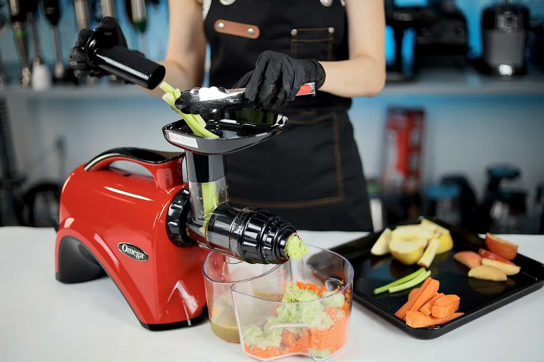 Person juicing apples, carrots, and celery using the Omega NC900 juicer