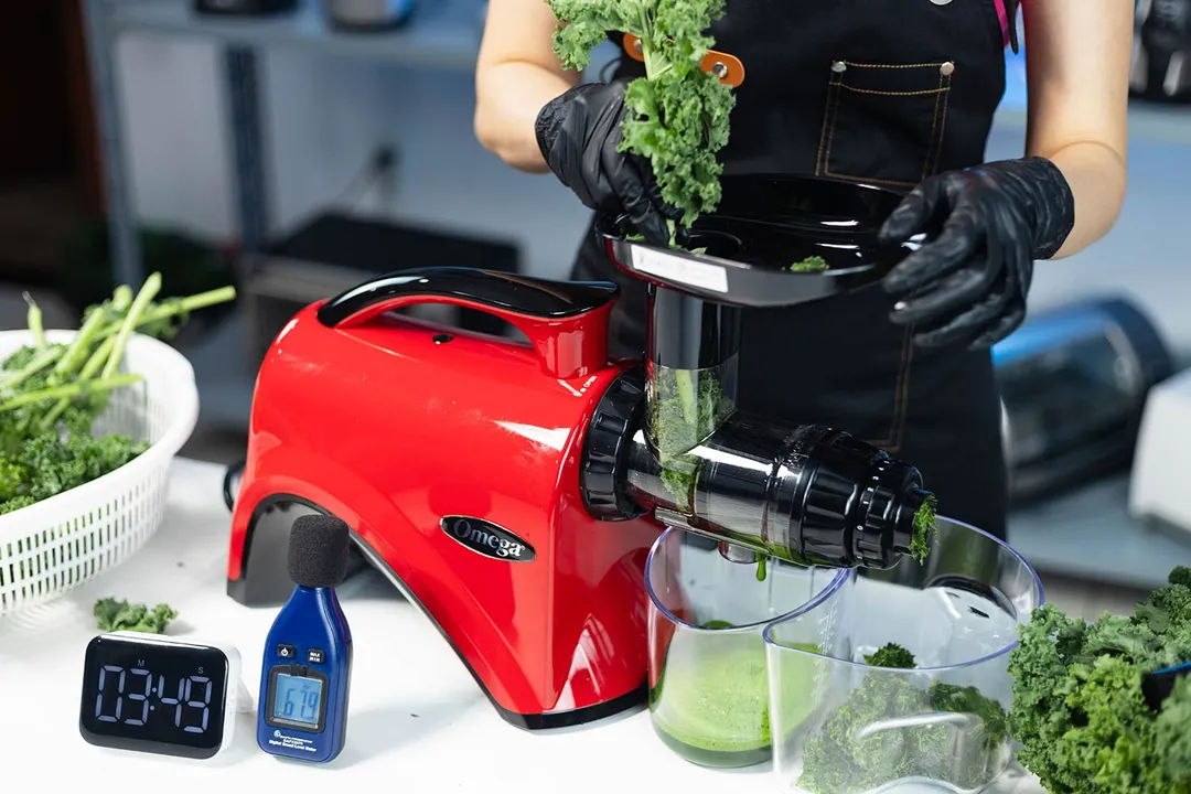 Person juicing kale leaves using the Omega NC900 masticating juicer