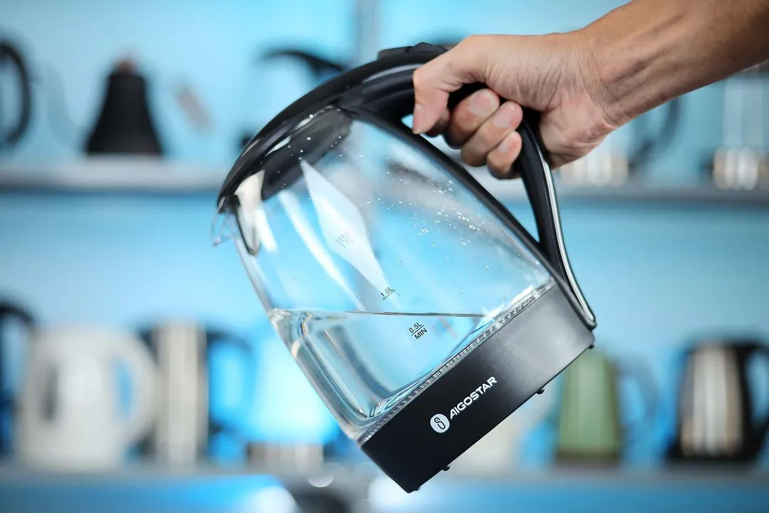 A hand holding the Aigostar Electric Kettle 300104LCB by its handle.