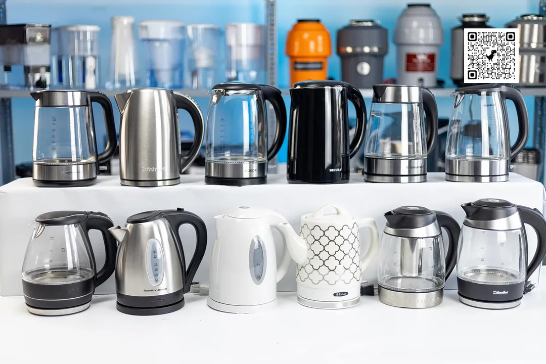 Seven best electric kettles within a line-up of twelve. In the background is a shelf of 6 water pitchers on the left and 5 garbage disposals on the right.