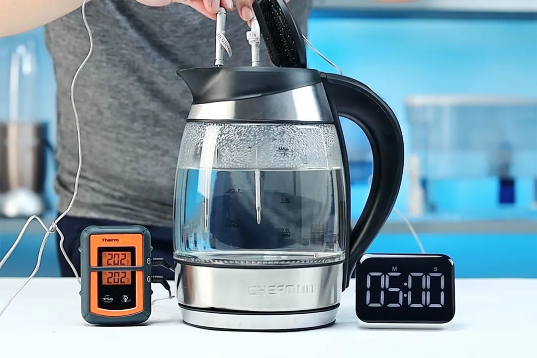 On the right is a Thermo Pro two-probe digital thermometer displaying 202°F for both probes. In the middle is the Chefman Electric Kettle with 5 Presets (RJ11-17-CTI-RL) with 1.5 liters of water and two probes inside. On the right is a digital timer displaying 5 minutes on the countdown.