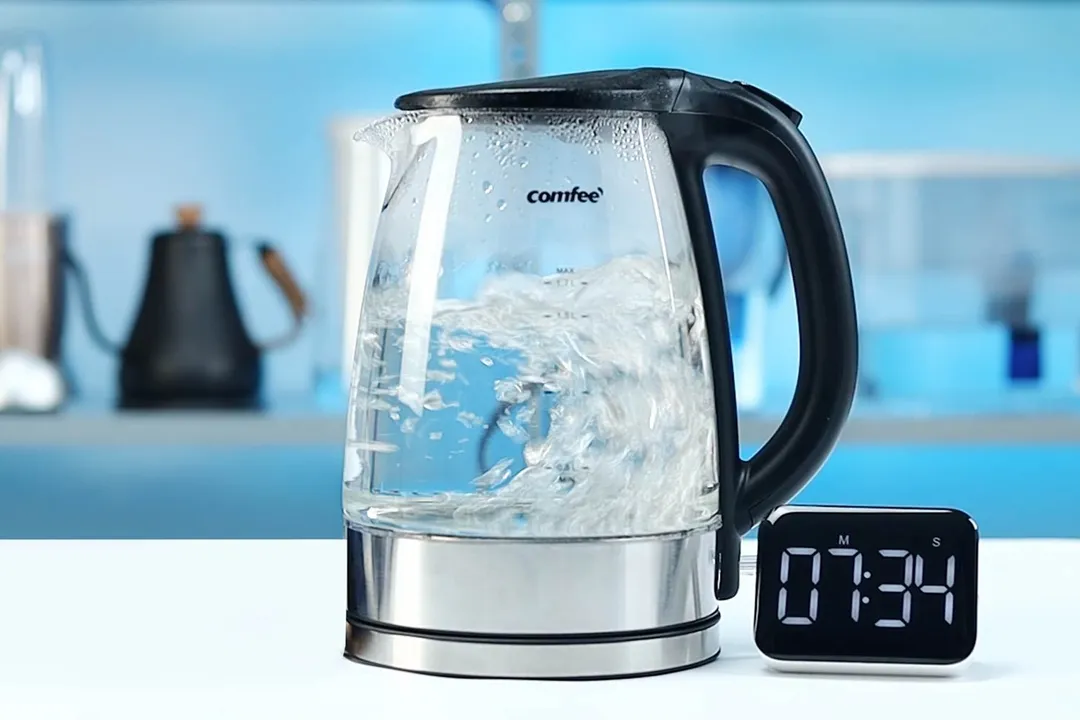 1.5 liter of water boiling inside the Comfee Glass Electric Kettle (CEKG003). The digital timer displays 7 minutes and 34 seconds.