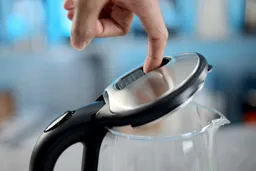 A finger opening the clip-lock for the stainless steel lid of the Dezin Electric Glass Kettle DZ380.