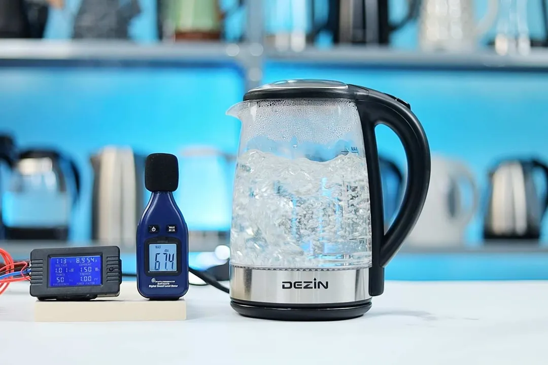 The Dezin Electric Glass Kettle DZ380 is boiling 1.5 liters of water. The noise meter displays the maximum sound pressure level to be 67.4 dB. The power meter reads 113 V, 8.954 A, 1.01 kW, 150 Wh, 50 Hz, and 1.0 PF.