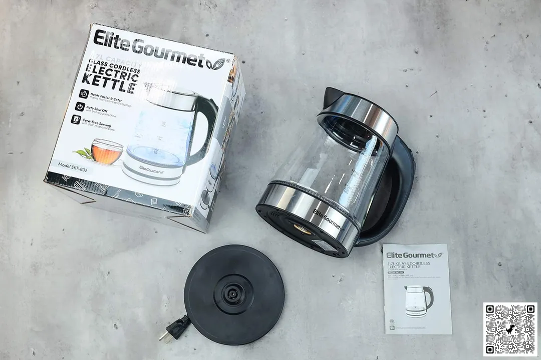 On the upper right is the Elite Gourmet Electric Glass Kettle (EKT-602). On the left is a cardboard box. Below the kettle, on the right is an instruction manual and on the left is the power base.
