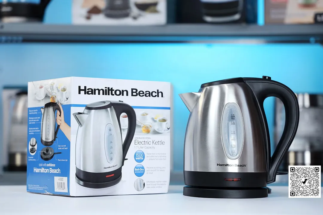The Hamilton Beach Electric Kettle (40880) on the right and its cardboard box on the left. In the background is a shelf with different electric kettles.