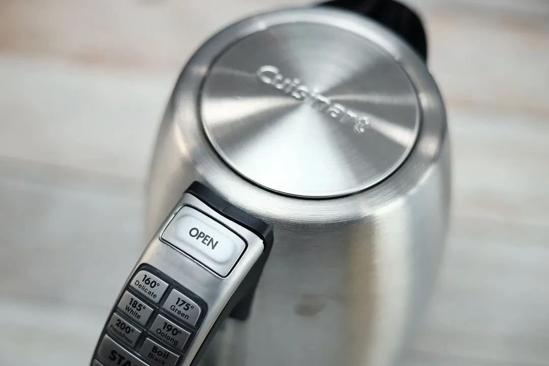 The lid is pop-up button of the Cuisinart Stainless Steel Electric Kettle with 6 Preset Temperatures (CPK-17P1 PerfecTemp) is located on its handle.