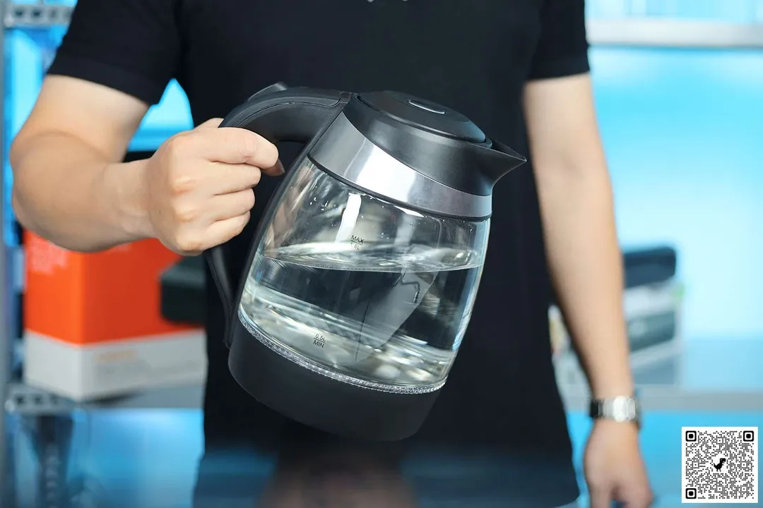 A person holding the Mueller Ultra Electric Kettle (M99S) by its handle.