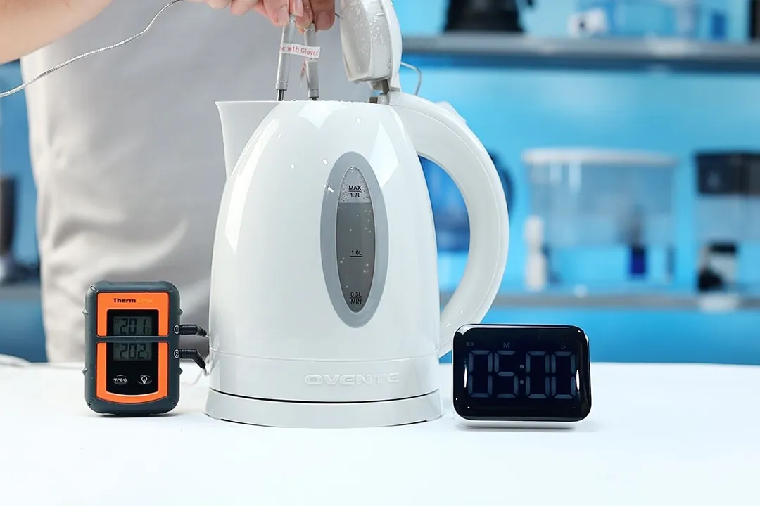 On the right is a Thermo Pro two-probe digital thermometer displaying 201°F for both probes. In the middle is theOvente Electric Kettle KP72W  with 1.5 liters of water and two probes inside. On the right is a digital timer displaying 5 minutes on the countdown.
