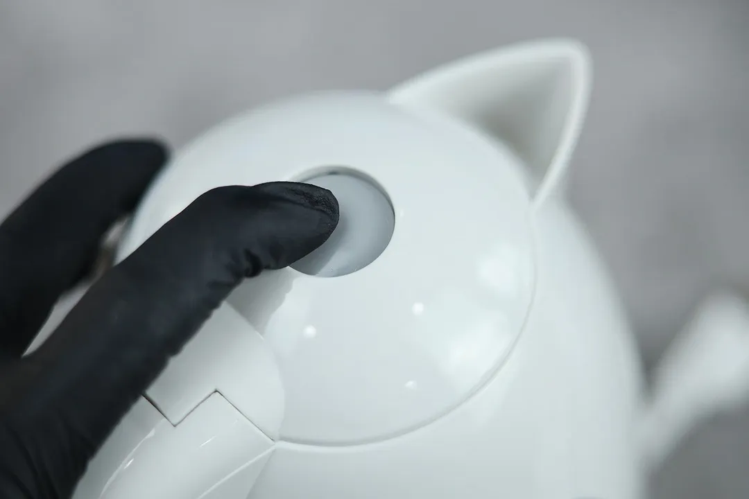 The white pop-up lid of the Ovente Electric Kettle KP72W has a button in the middle.