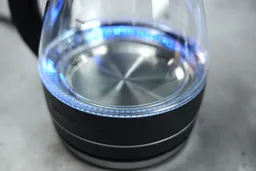 The heating plate with a LED ring around it glowing blue of the Ovente Electric Glass Kettle (KG83B).