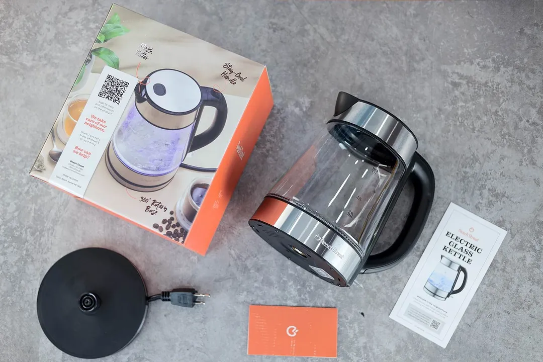 On the upper right is the Peach Street Electric Kettle PE-1300. On the left is a cardboard box. Below the kettle, on the right is an instruction manual and on the left is the power base.