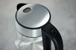 The stainless steel pop-up lid of the Peach Street Electric Kettle PE-1300 and its button on the handle.