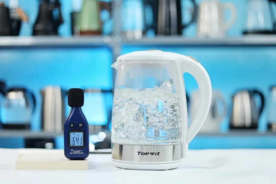 The Topwit Glass Electric Tea Kettle T630 is boiling 1.5 liters of water. The noise meter displays the maximum sound pressure level to be 64.1 dB.