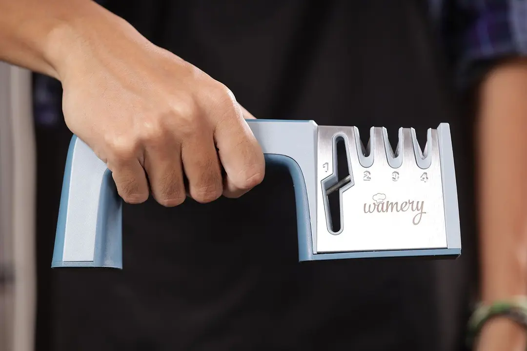 A hand holding the Wamery 4-stage manual knife sharpener