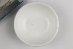 A bowl containing metal sharpening residue next to the base of the Wamery sharpener