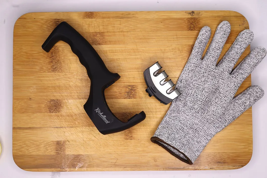 The base and separated working section of the Kitchellence, and a glove, all on a cutting board