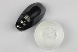 Top view of a bowl containing metal sharpening residue next to the KitchenIQ sharpener