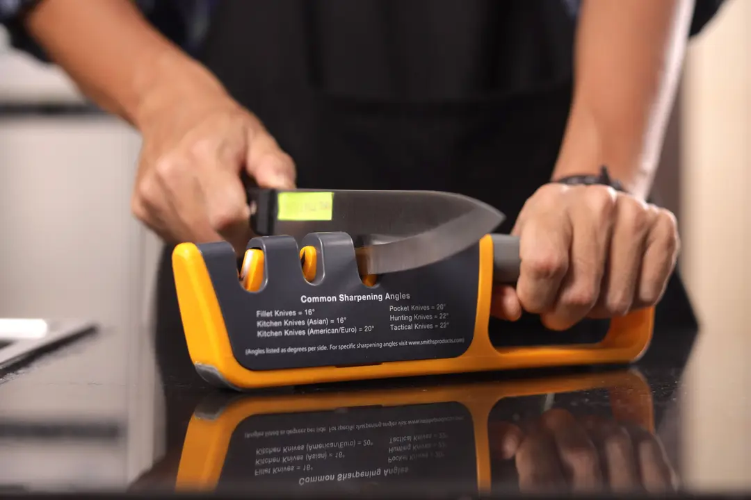 A person sharpening a knife with the Smith’s 50264 adjustable knife sharpener