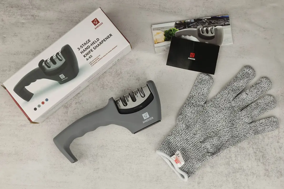 The Amesser sharpener next to its package box, a glove, and promotional leaflets
