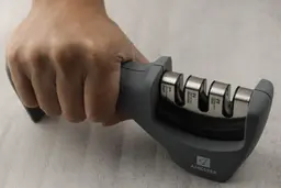 A hand gripping on the Amesser A-65 manual sharpener