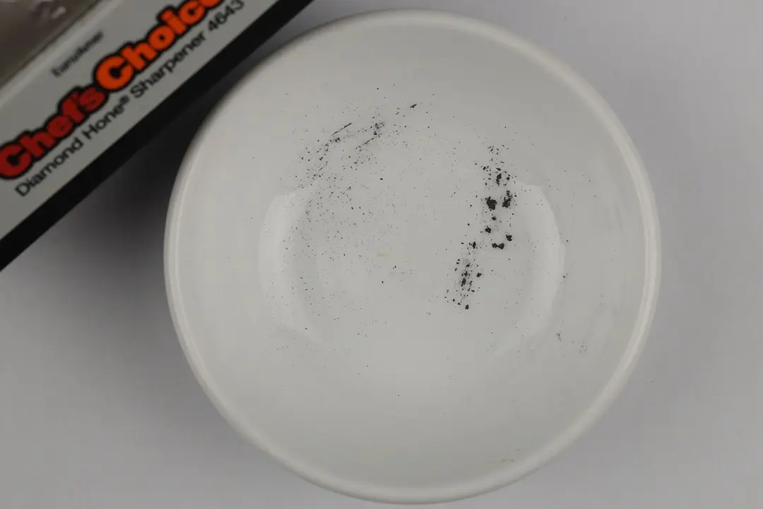 A bowl containing metal sharpening residue next to the base of the Chef's Choice AngleSelect sharpener