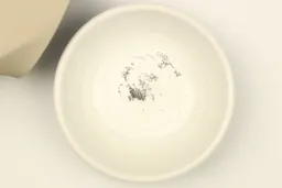 A bowl containing metal sharpening residue next to the base of the Gorilla Grip sharpener