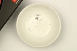 A bowl containing metal sharpening residue next to the Zwilling sharpener