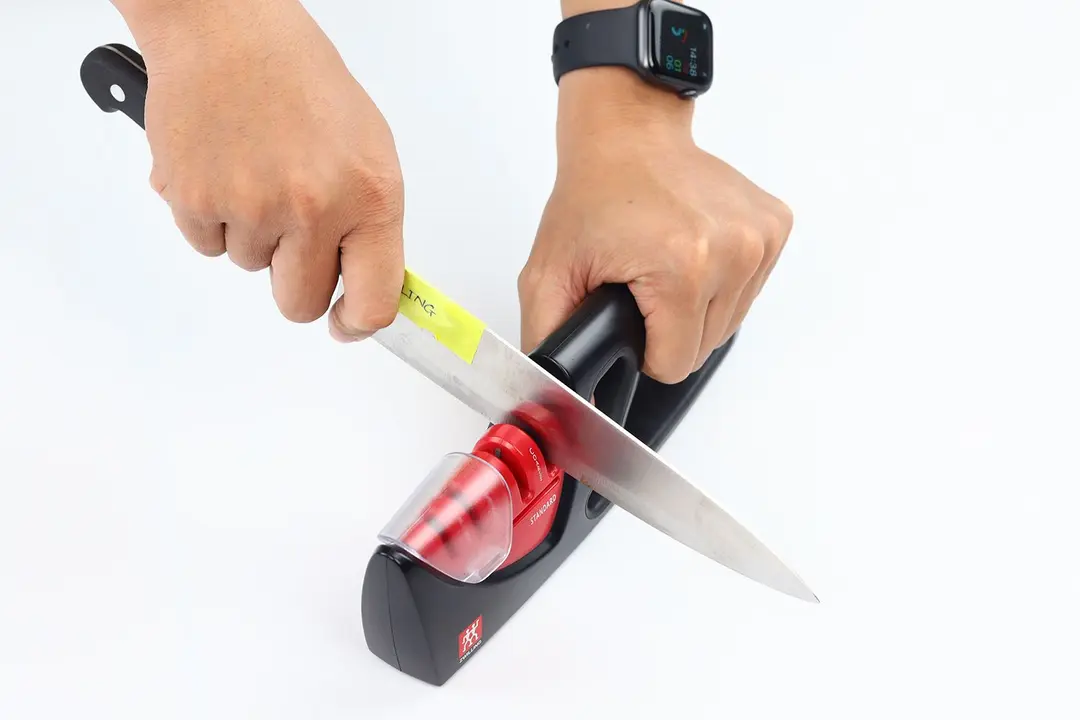 2 hands holding and sharpening a kitchen knife with the Zwilling Henckels 4 stage knife sharpener