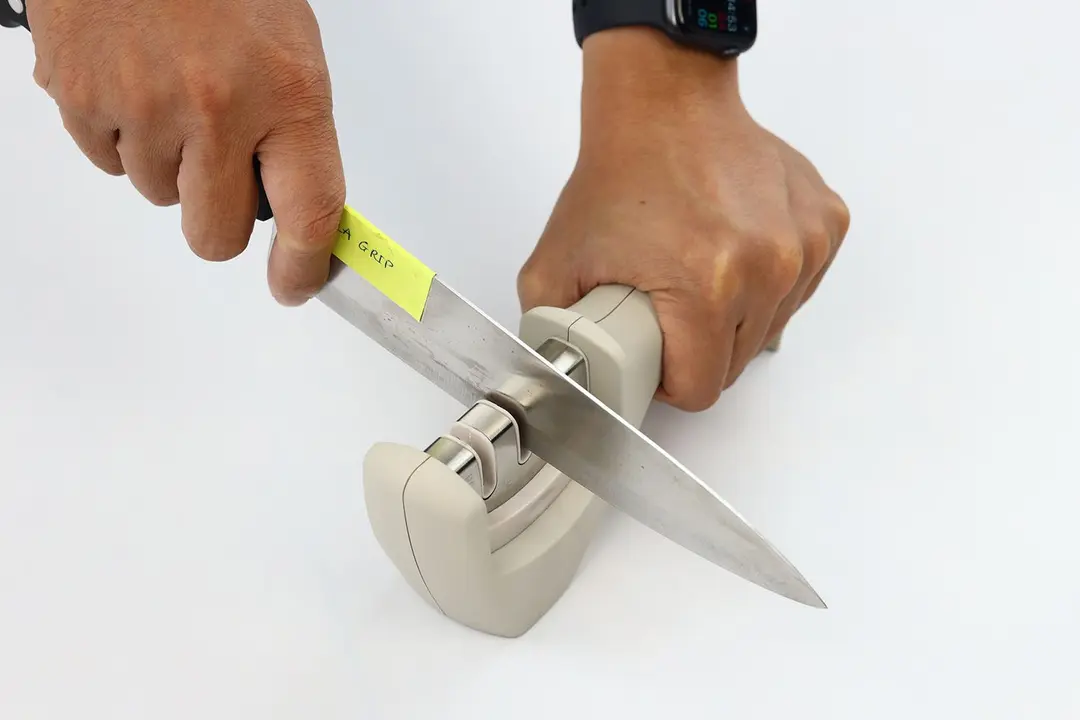 Two hands holding and sharpening a kitchen knife with the Gorilla Grip sharpener