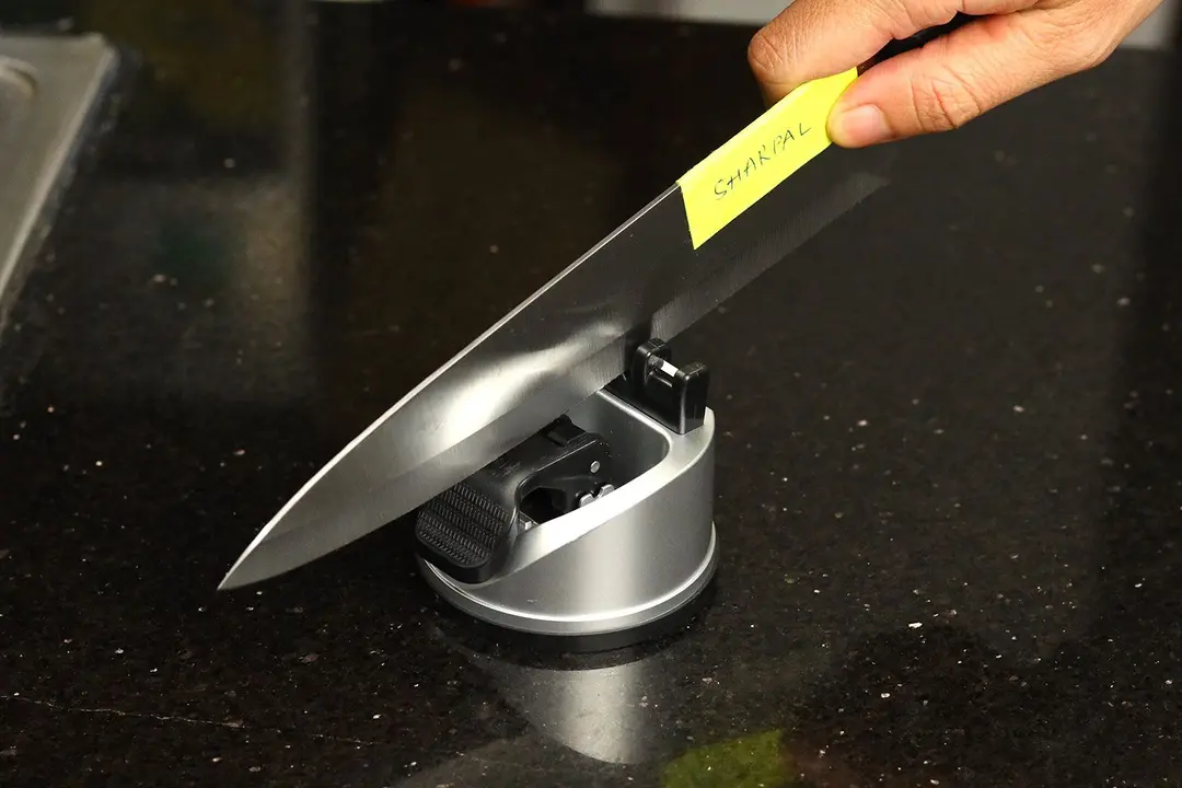 A kitchen knife sharpened with the Sharpal sharpener on a countertop