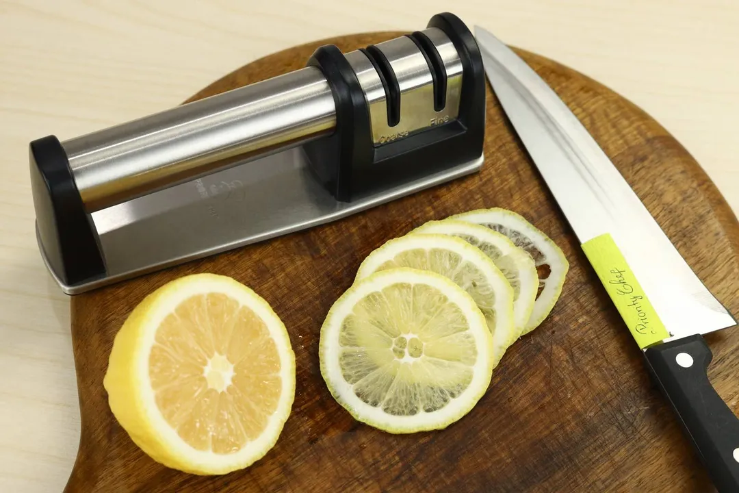 The Priority Chef 2-stage knife sharpener on a cutting board with a kitchen knife and slices of lemon.