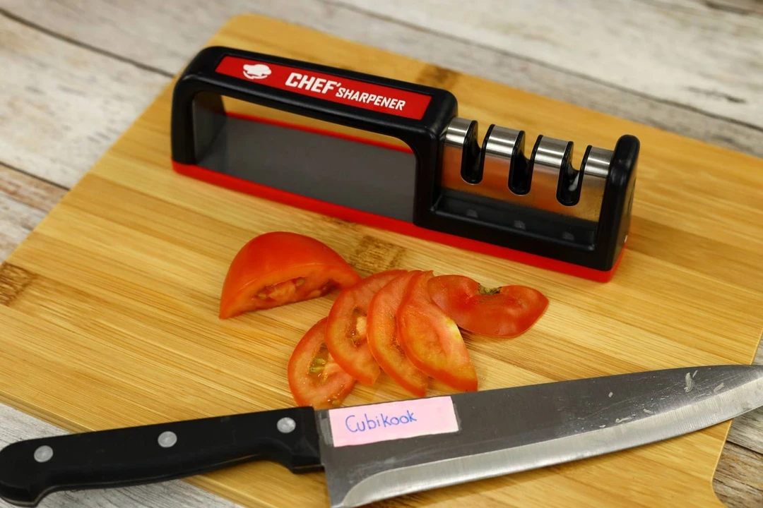 The Cubikook Chef Sharpener 3-stage knife sharpener on a cutting board with a knife and slices of tomatoes