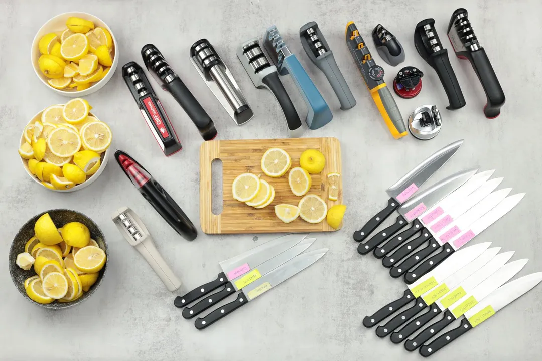 Devices tested to find out the best manual sharpeners 2024, including the Cubikook, Chef’s Choice Pronto, Kitchellence, among others. Included are test knives and lemon slices in three bowls and on a cutting board.