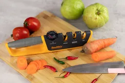 The Smith’s 50264 adjustable manual sharpener on cutting board, kitchen knife, carrots and carrot slices, tomatoes, chilli peppers, guavas 