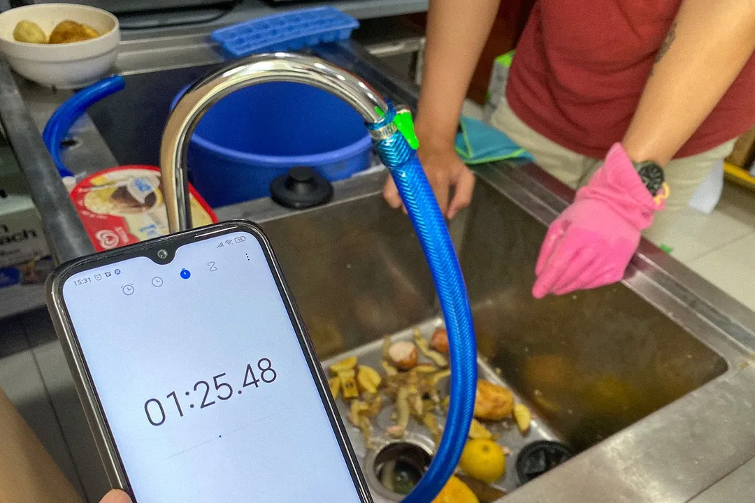 Front: smartphone timer; back: person wearing a glove leaning against a kitchen sink with vegetable scraps in it.